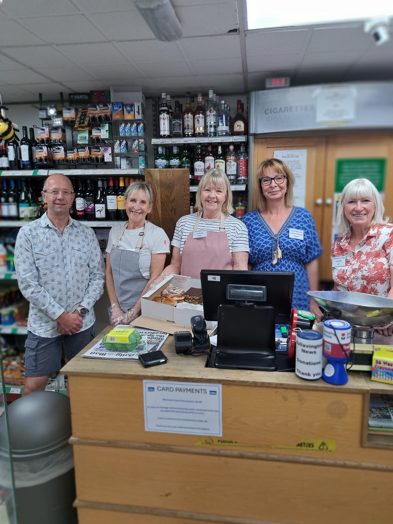 Photograph of 5 of the volunteers that work in the shop, behind the till counter